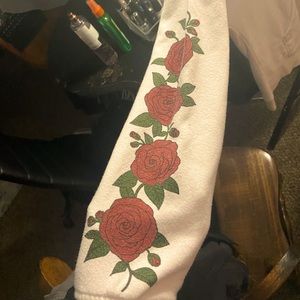 This is a white hoodie with a small rose on the front and roses on both sleeves